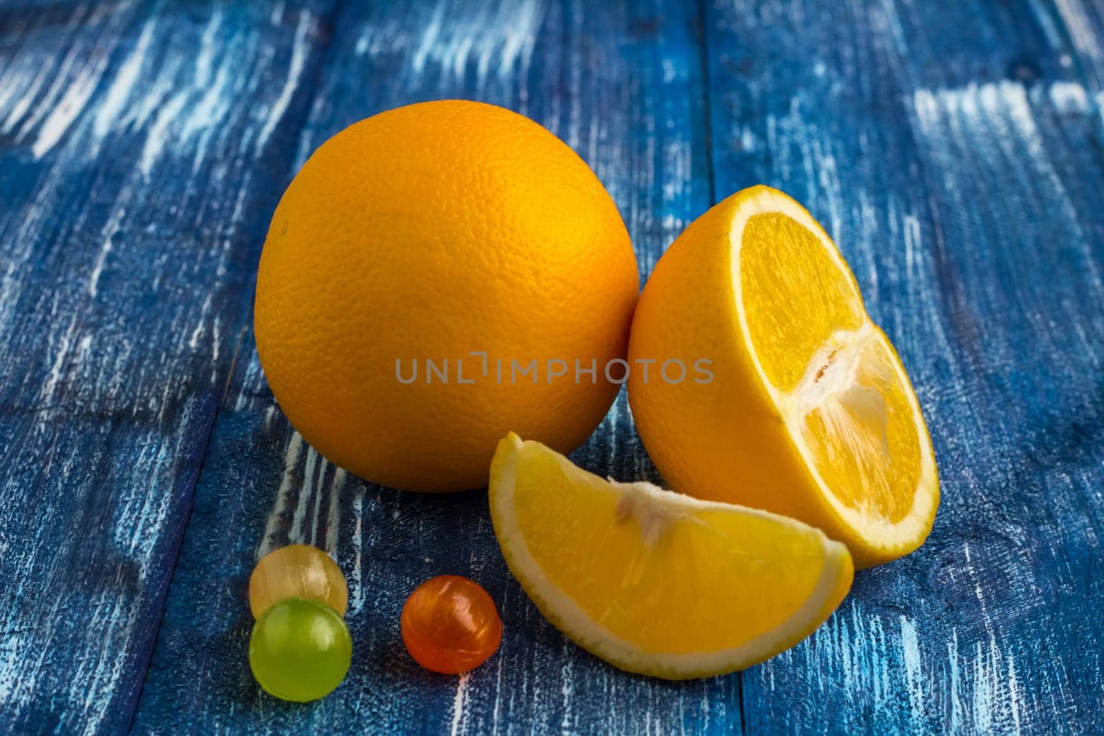 Still life composition of oranges and candies on blue wood