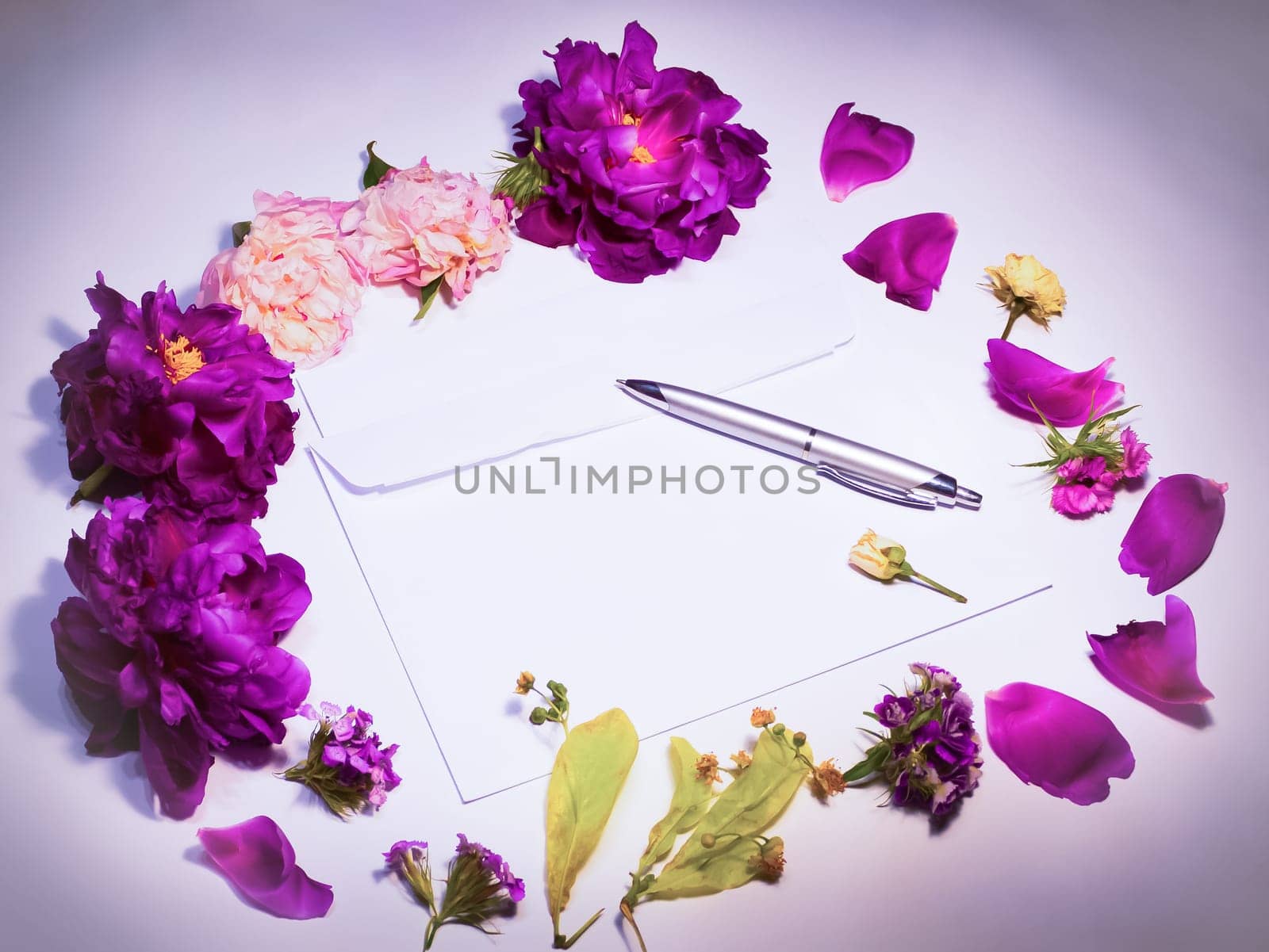 Flowers, envelope and pen on a lilac background