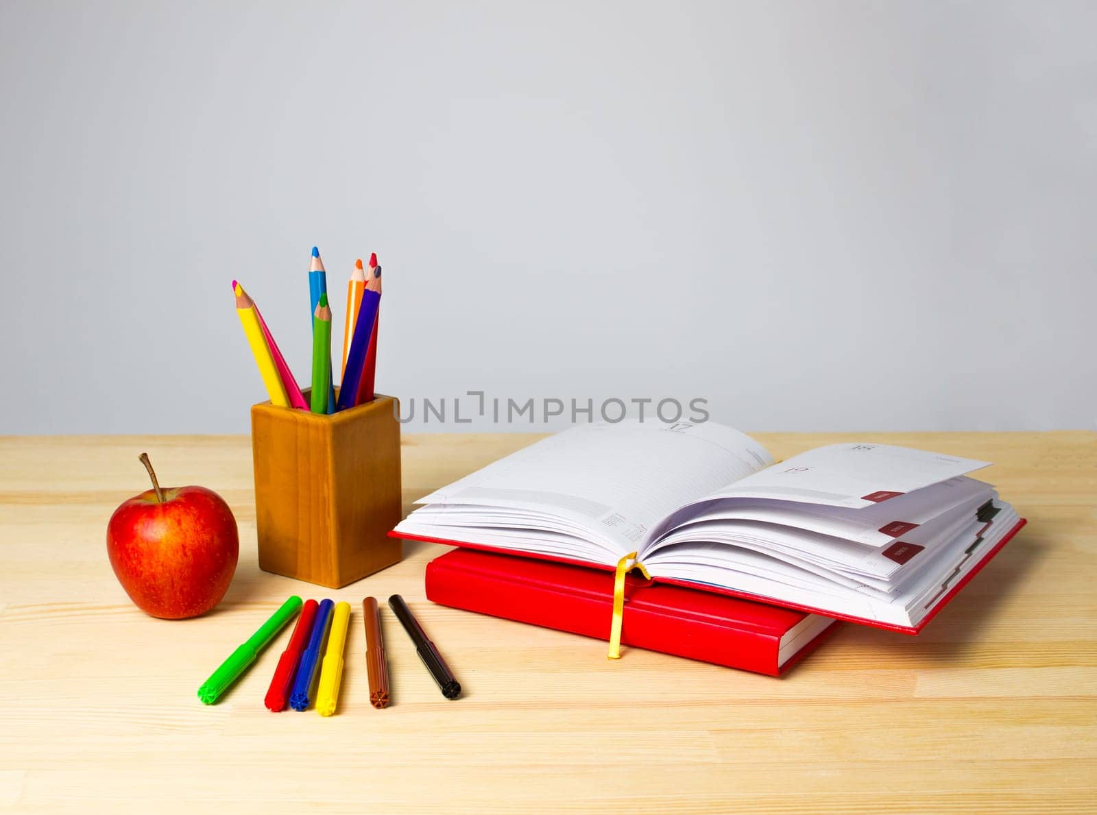 Back to school background with books, pencils and red apple over wooden table