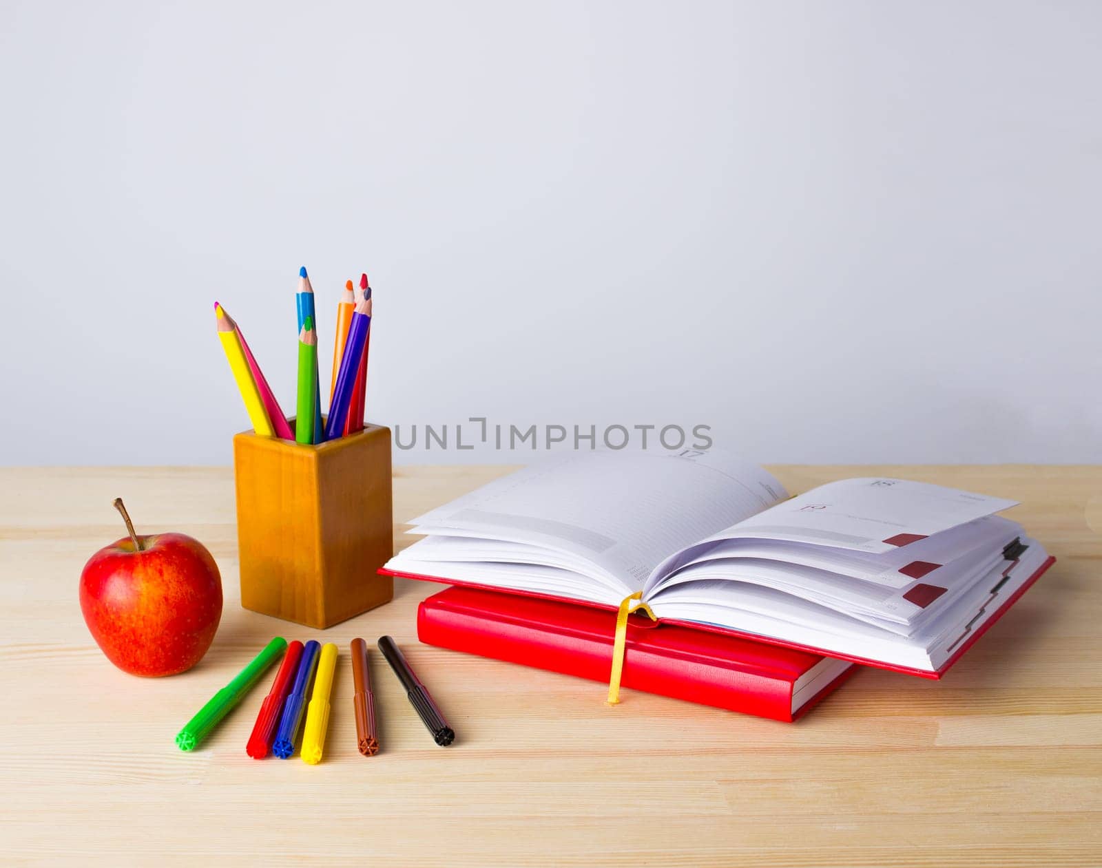 Back to school background with books, pencils and red apple over wooden table
