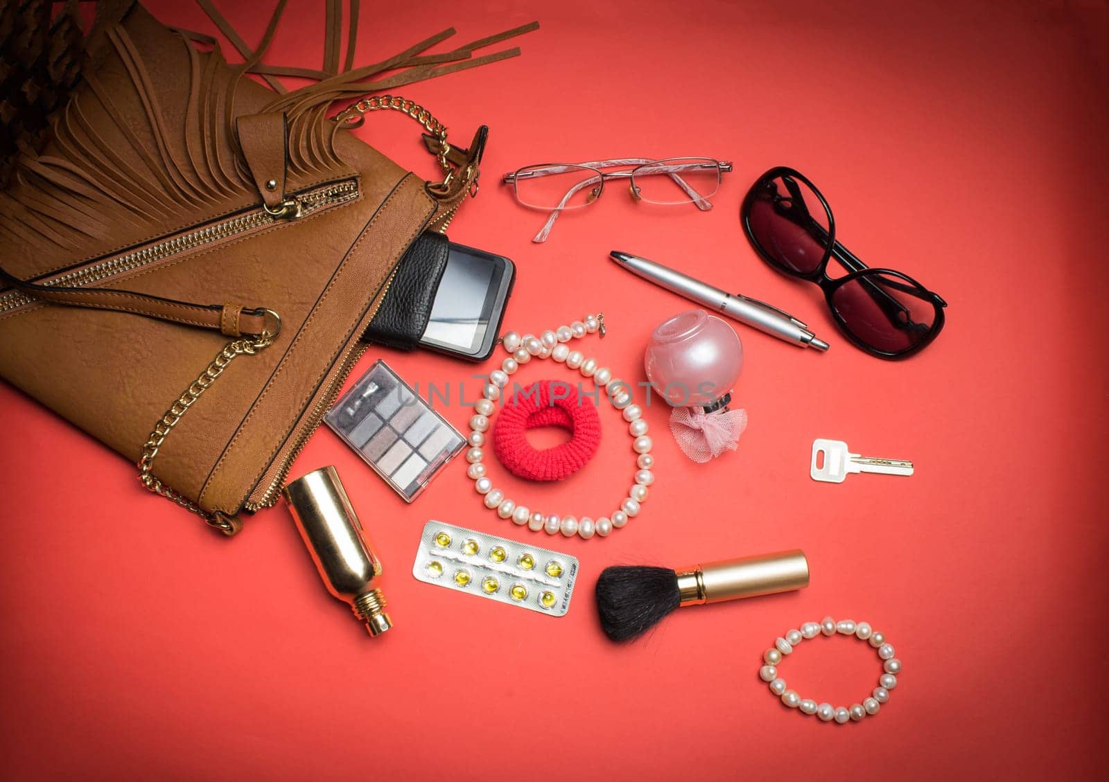 Top view of the female accessories and phone on a red background