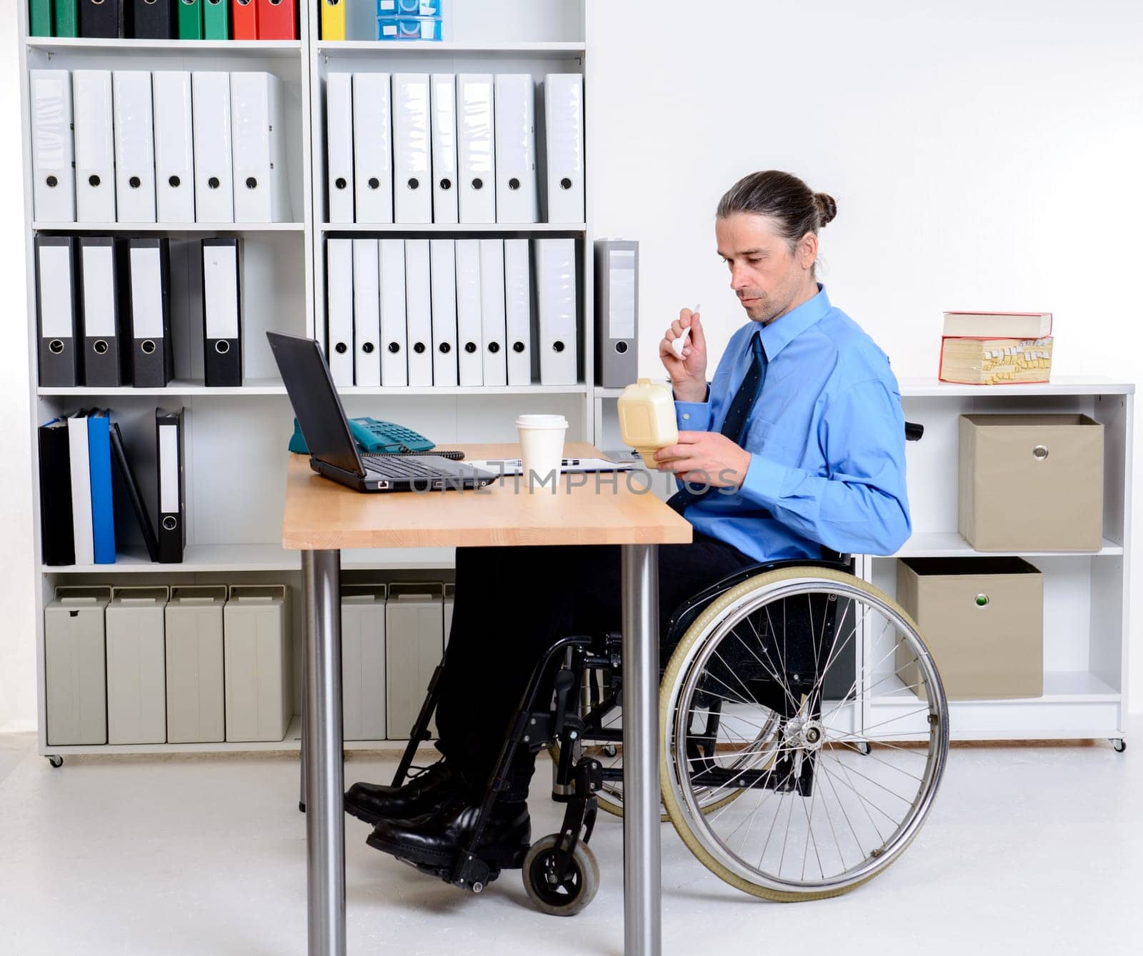 disabled business man in wheelchair eating in the office