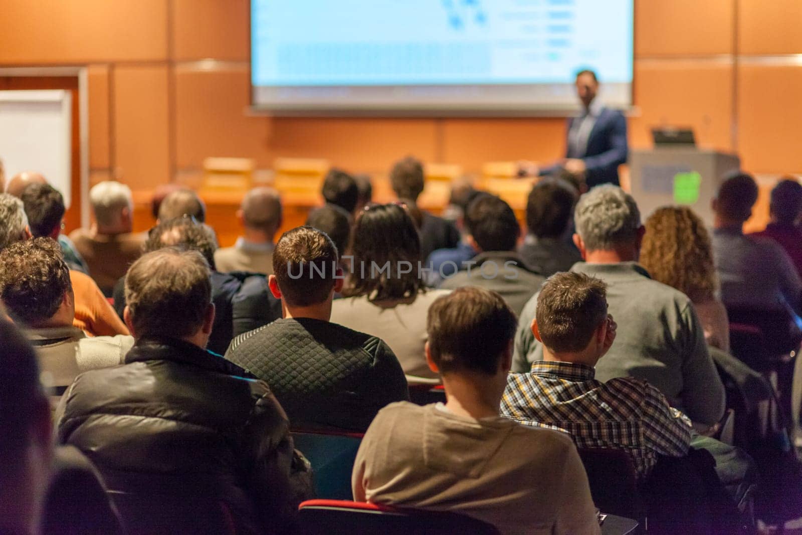 Speaker giving a talk in conference hall at business event. Audience at the conference hall. Business and Entrepreneurship concept.