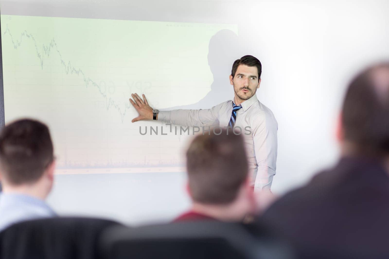 Business man making a presentation at office. Business executive delivering a presentation to his colleagues during meeting or in-house business training, explaining business plans to his employees.