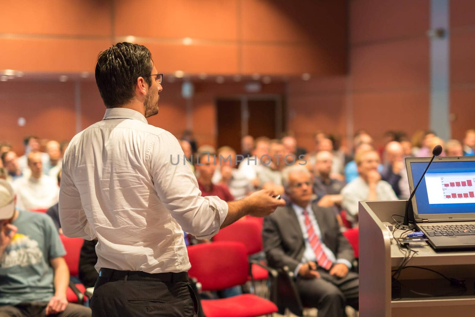 Speaker giving a talk on corporate Business Conference. Audience at the conference hall. Business and Entrepreneurship event.