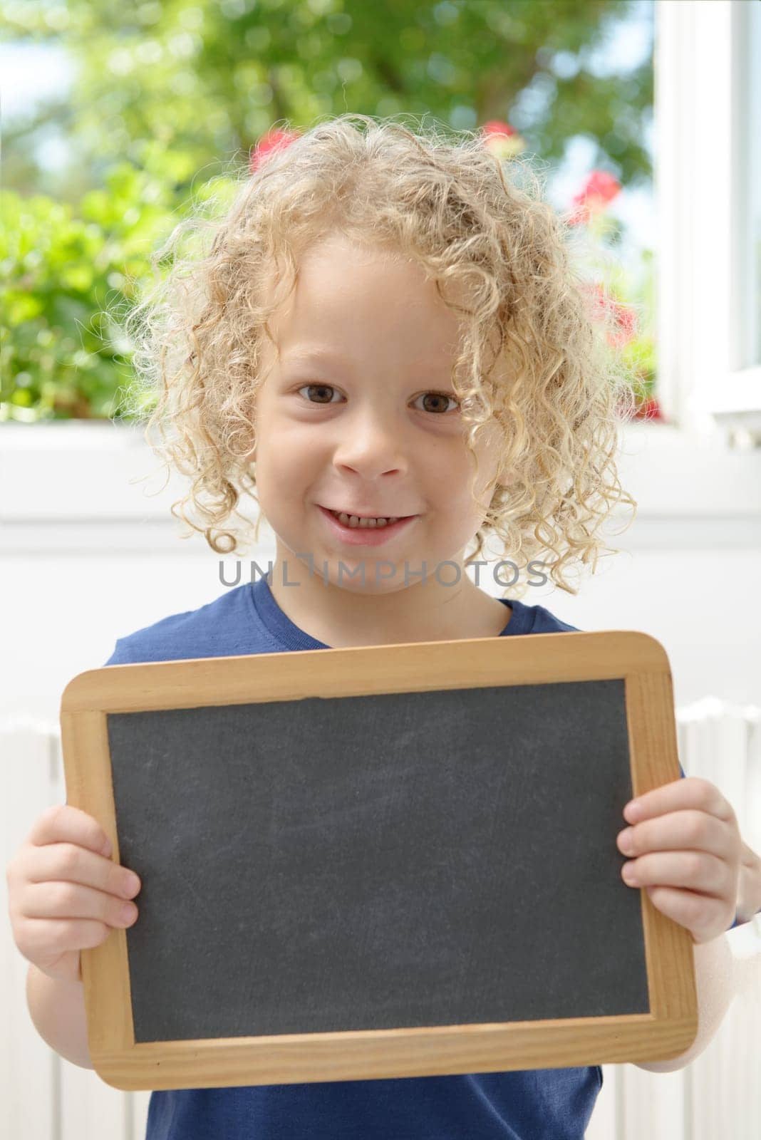 a little blond boy holding a chalkboard