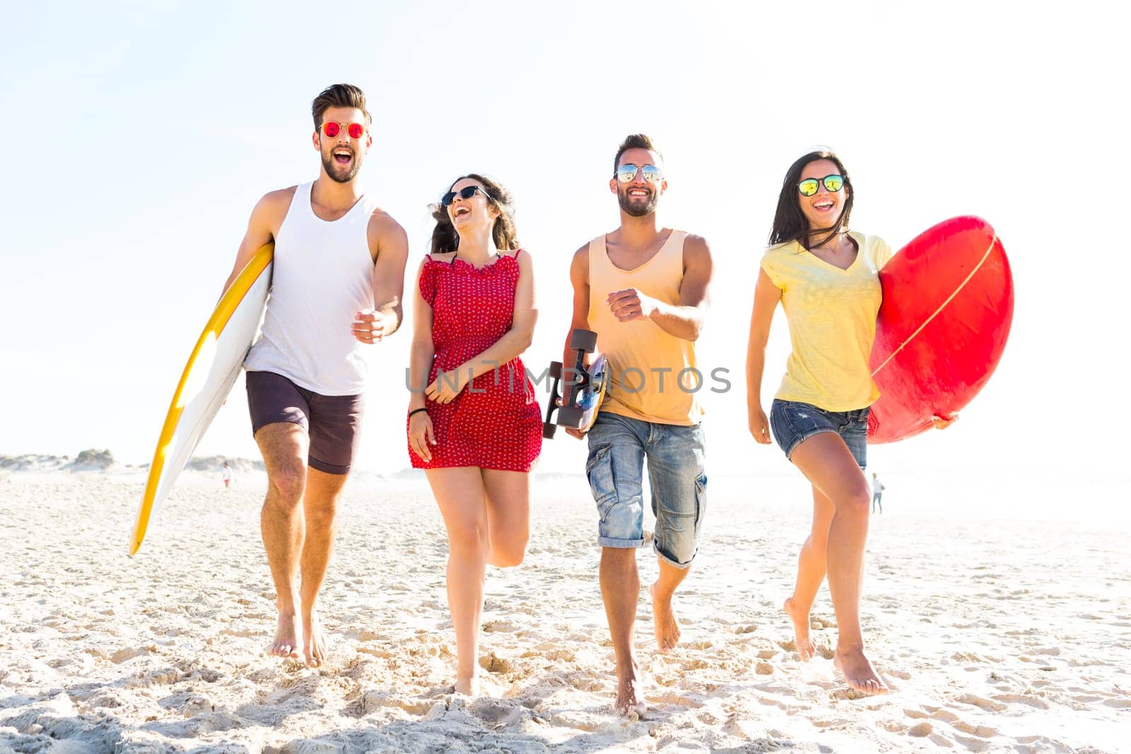Group of friends walking together at the beach and holding surfboards