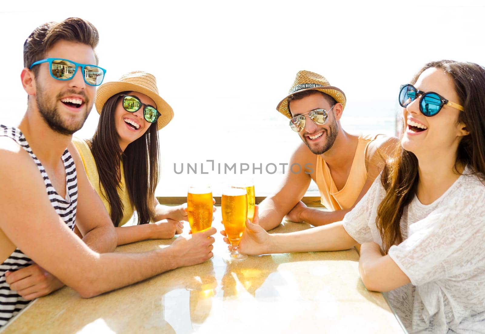 Friends having fun and drinking a cold beer at the beach bar