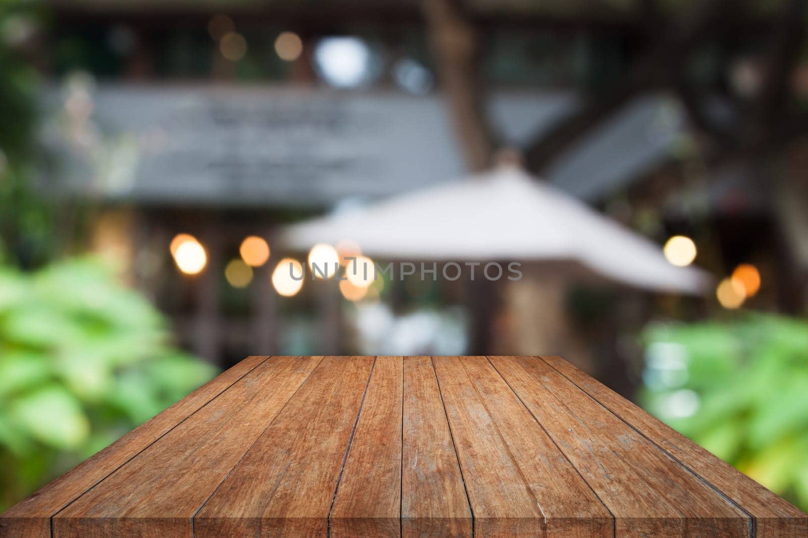 Perspective wooden table top with cafe blurred abstract background