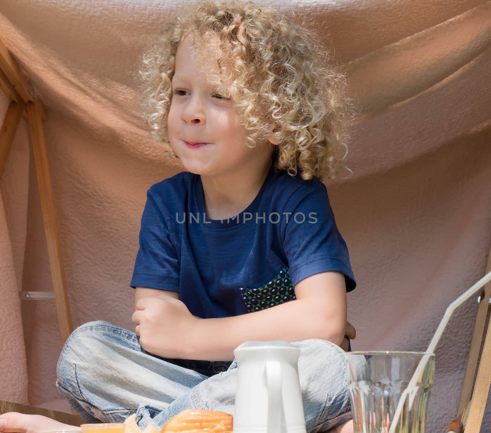 a boy with curly blond hair, to the outside