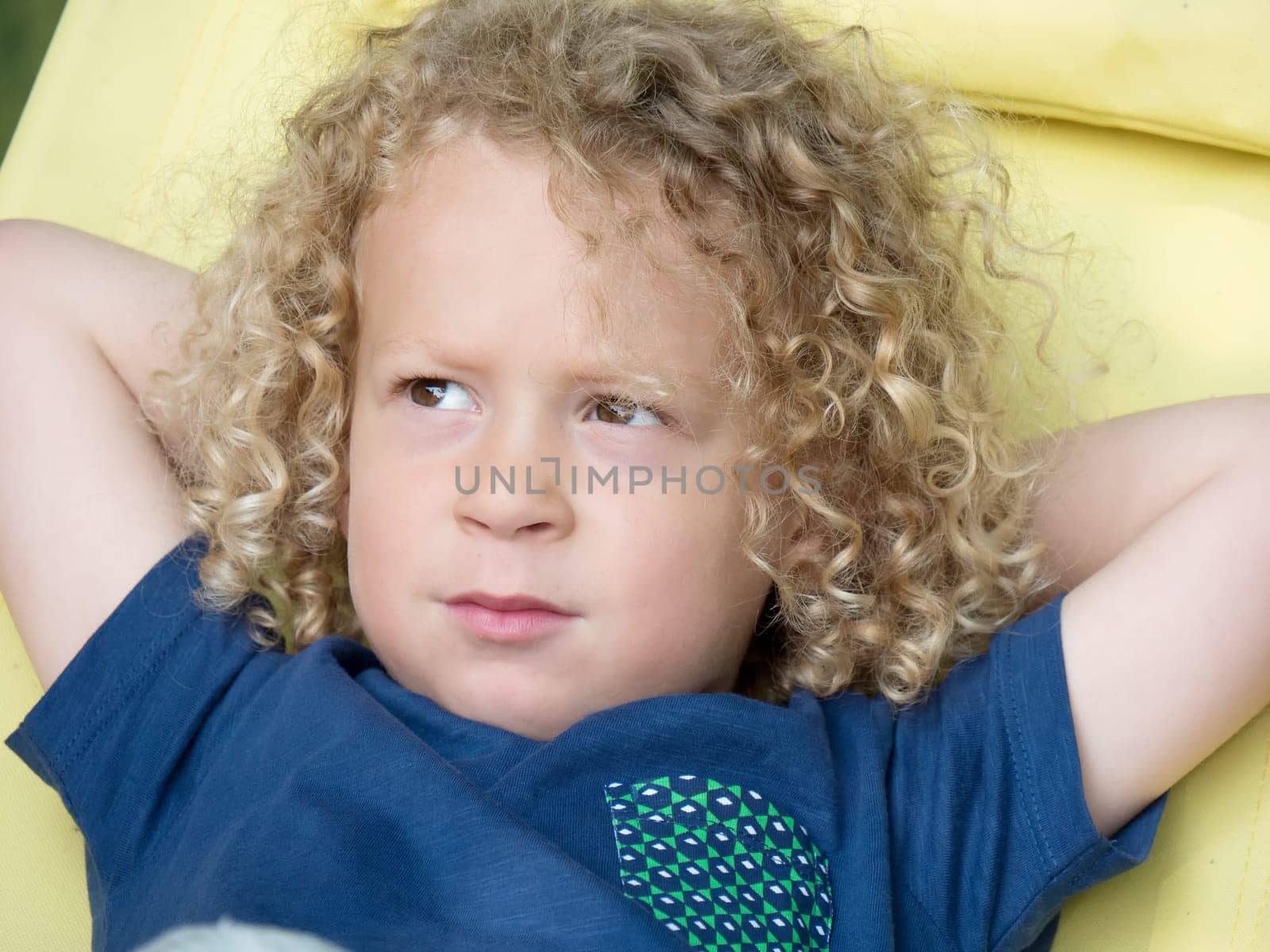 a boy with curly blond hair, to the outside