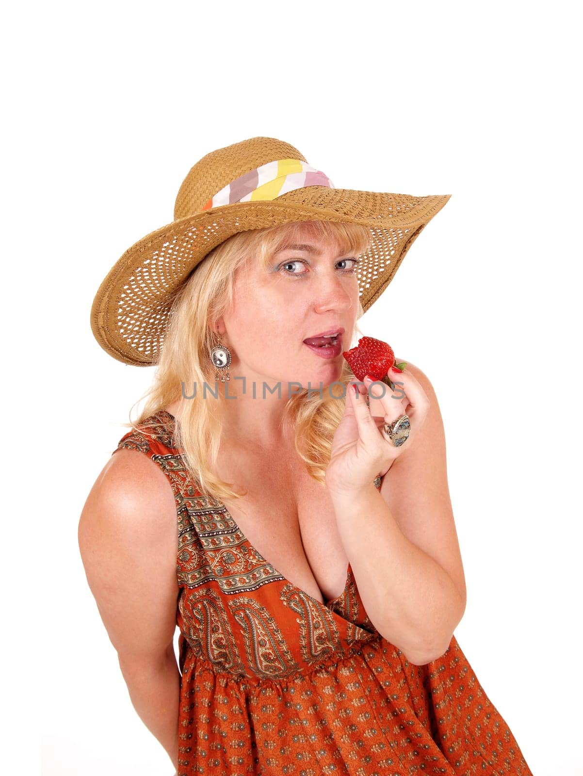 A closeup image of a nice woman eating a big strawberry with blue eye's.and a straw hat, isolated for white background..