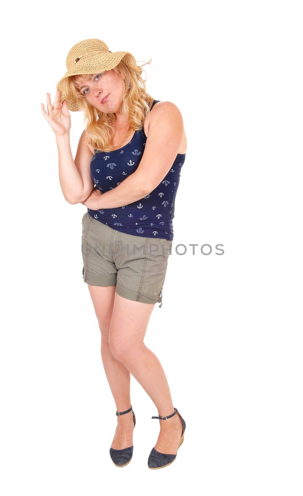 A middle age blond woman standing in shorts from the front wearing a.beige straw hat, isolated for white background..