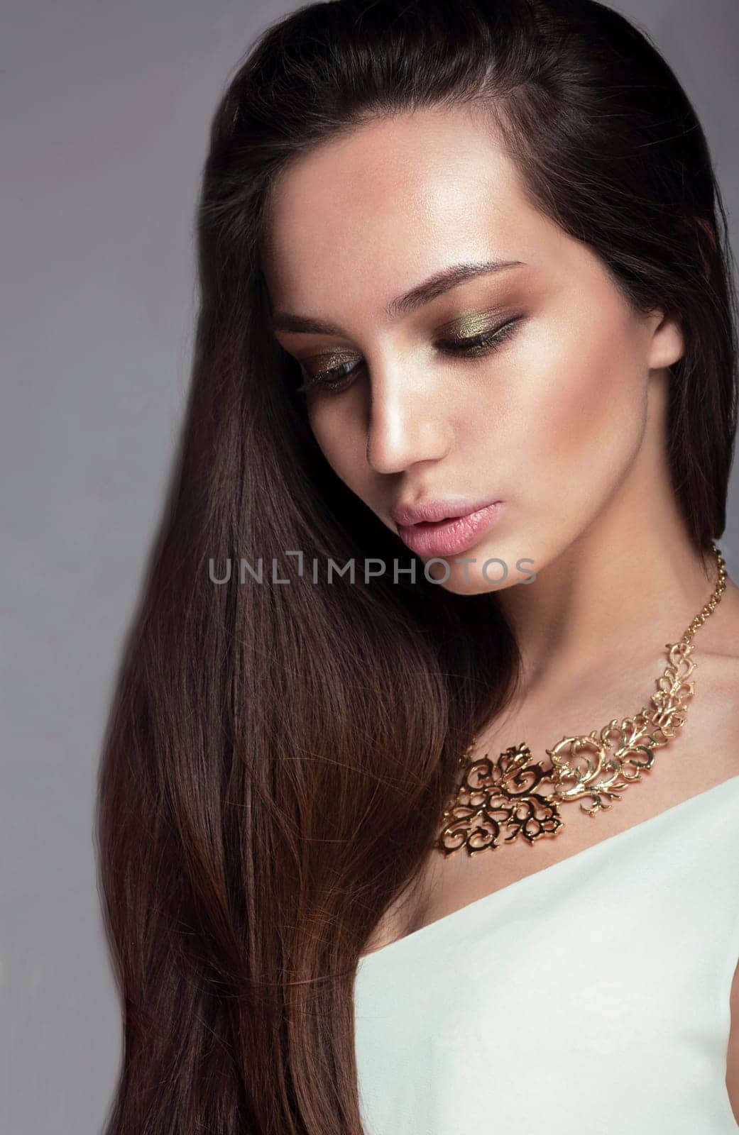 Glamour portrait of a woman looking down. Long hair, full lips, professional make-up.