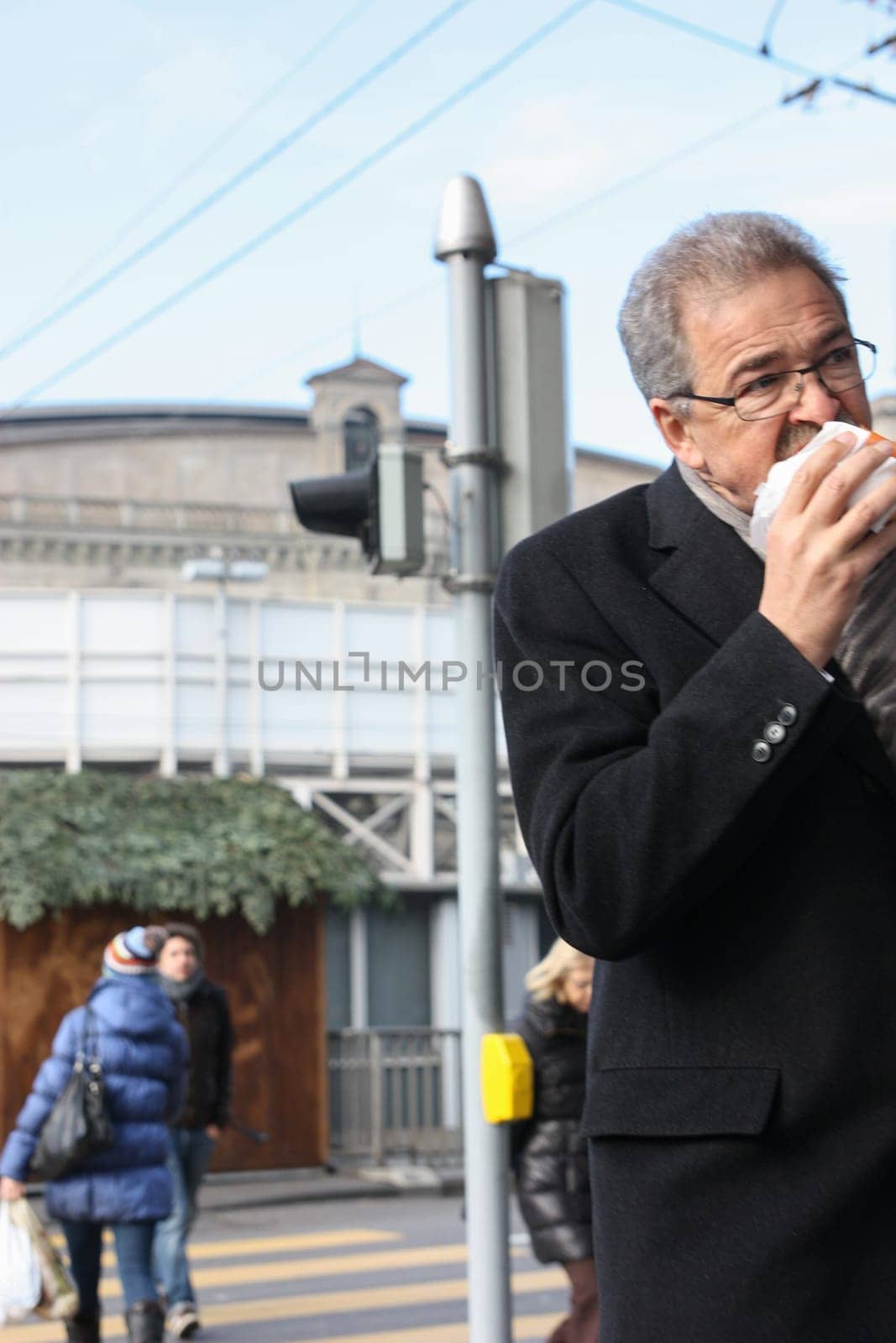 Zurich, Switzerland - November 29 2011. Ederly man eating a hamburger on the go.