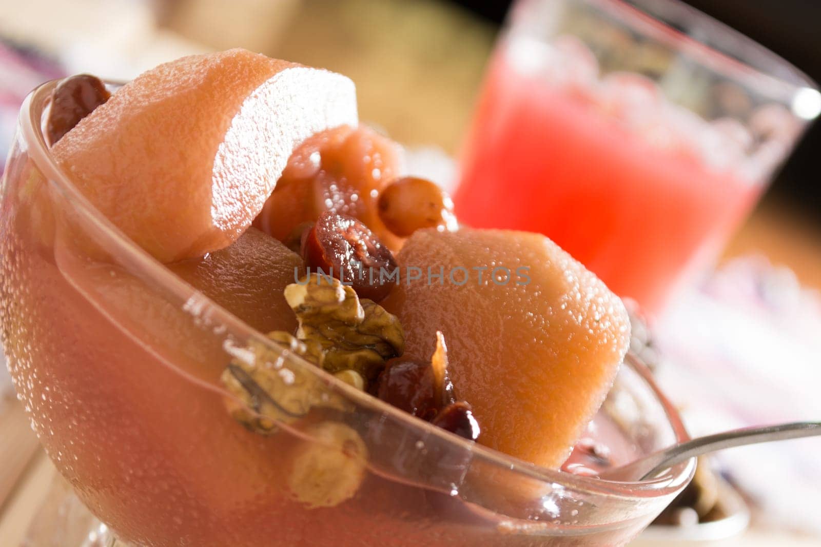 Apple compote with dried fruits in the cup on wooden table with decorative wallnuts