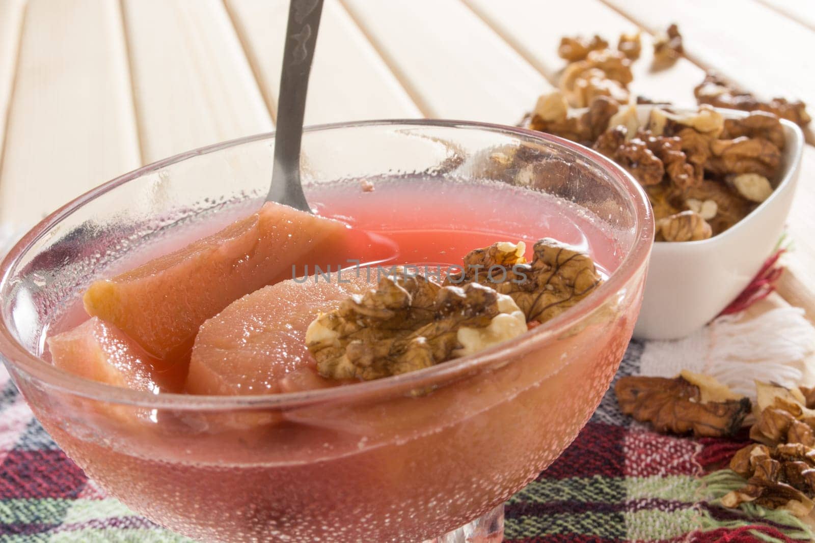 Apple compote with dried fruits in the cup on wooden table with decorative wallnuts