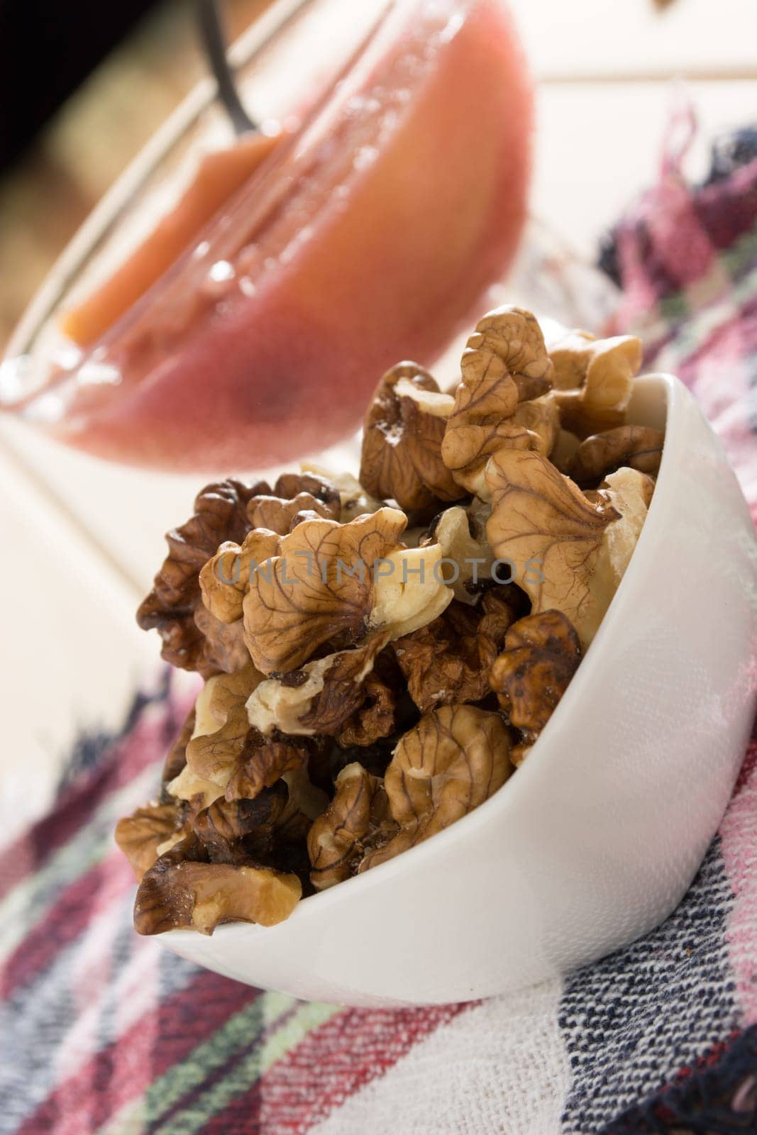 Apple compote with dried fruits in the cup on wooden table with decorative wallnuts