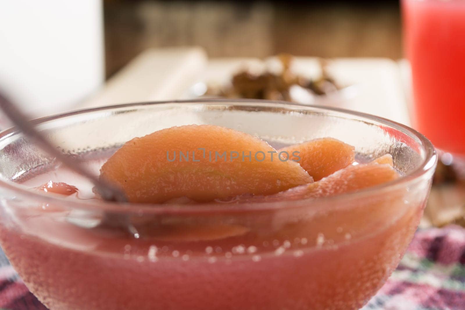 Apple compote with dried fruits in the cup on wooden table with decorative wallnuts