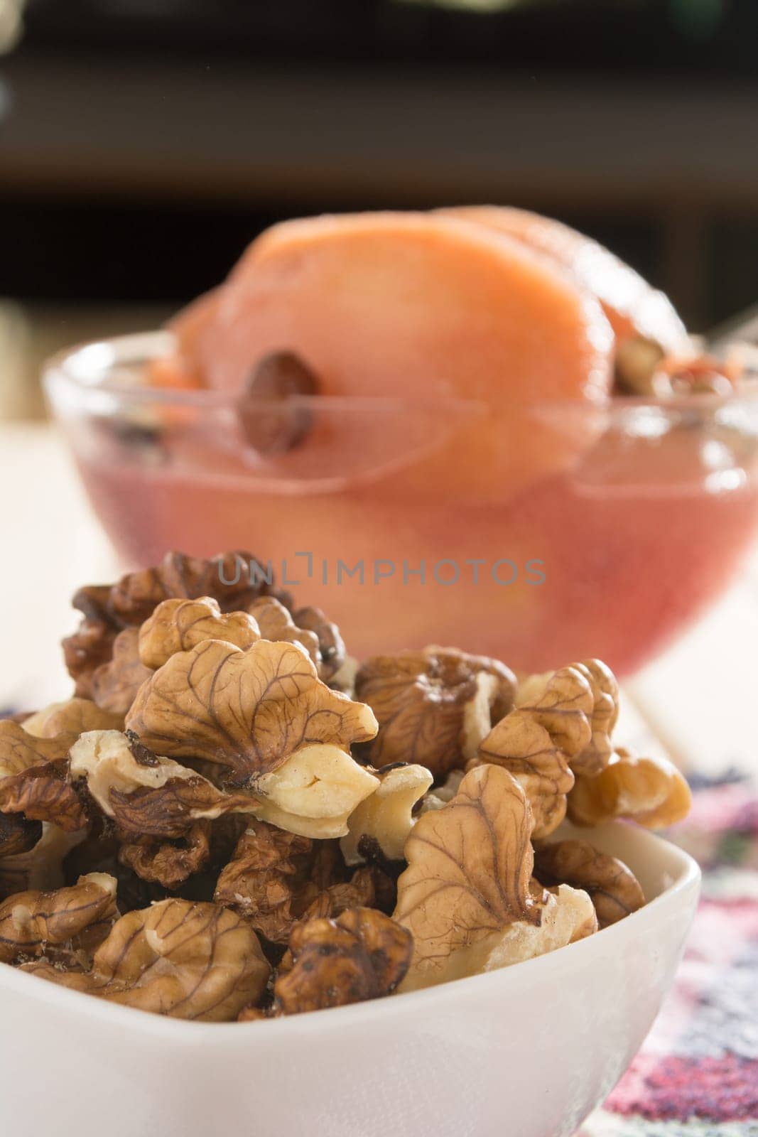 Apple compote with dried fruits in the cup on wooden table with decorative wallnuts
