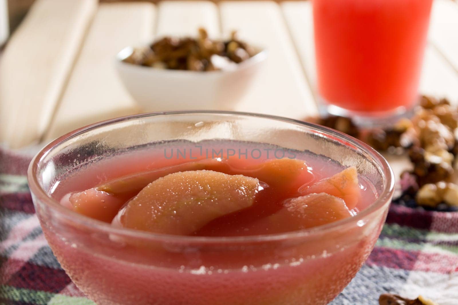 Apple compote with dried fruits in the cup on wooden table with decorative wallnuts