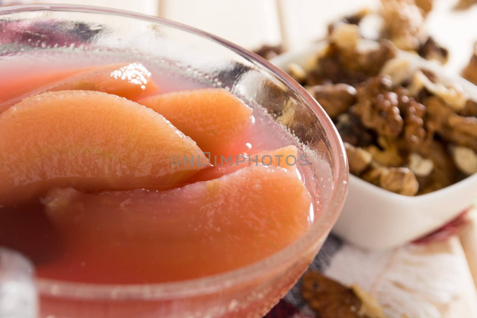 Apple compote with dried fruits in the cup on wooden table with decorative wallnuts
