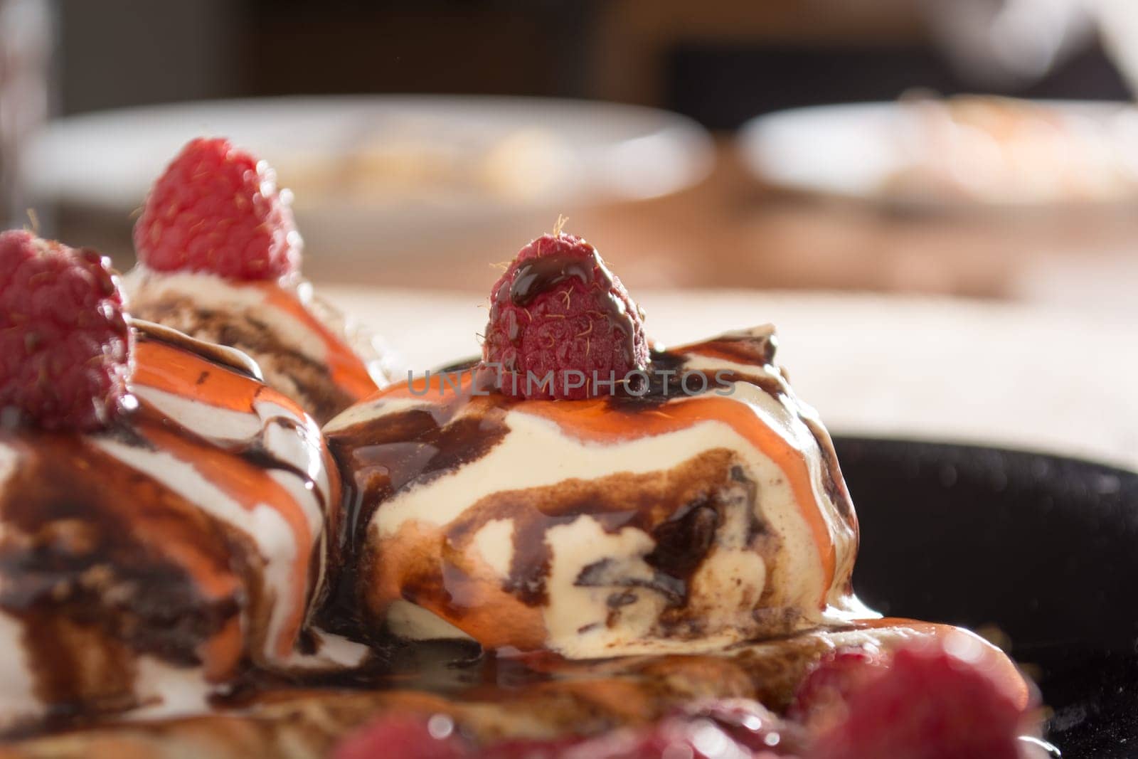 Fresh, golden pancakes with fruit and cream on a black plate with blurred background