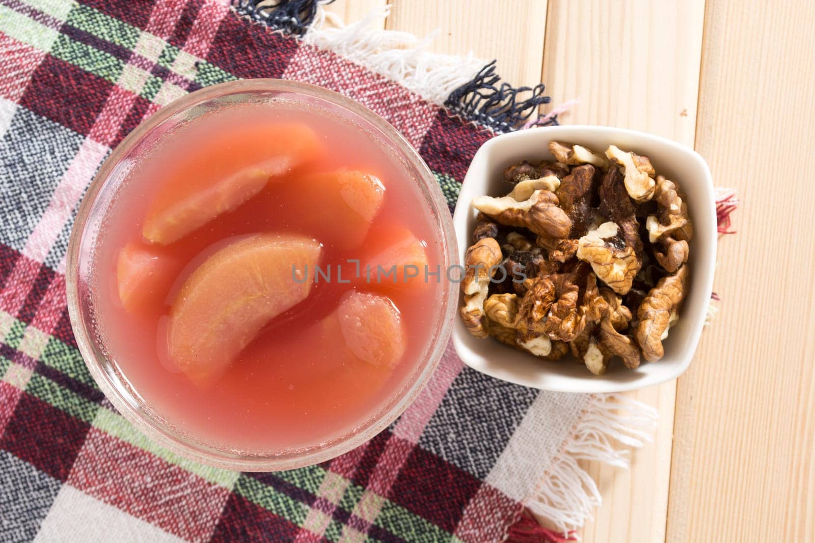 Apple compote with dried fruits in the cup on wooden table with decorative wallnuts