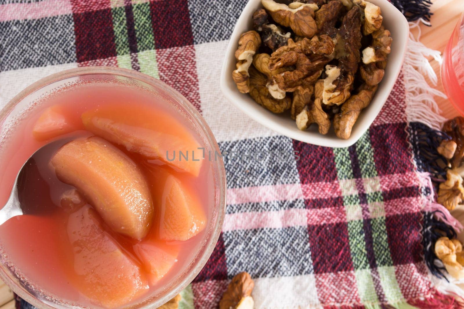 Apple compote with dried fruits in the cup on wooden table with decorative wallnuts