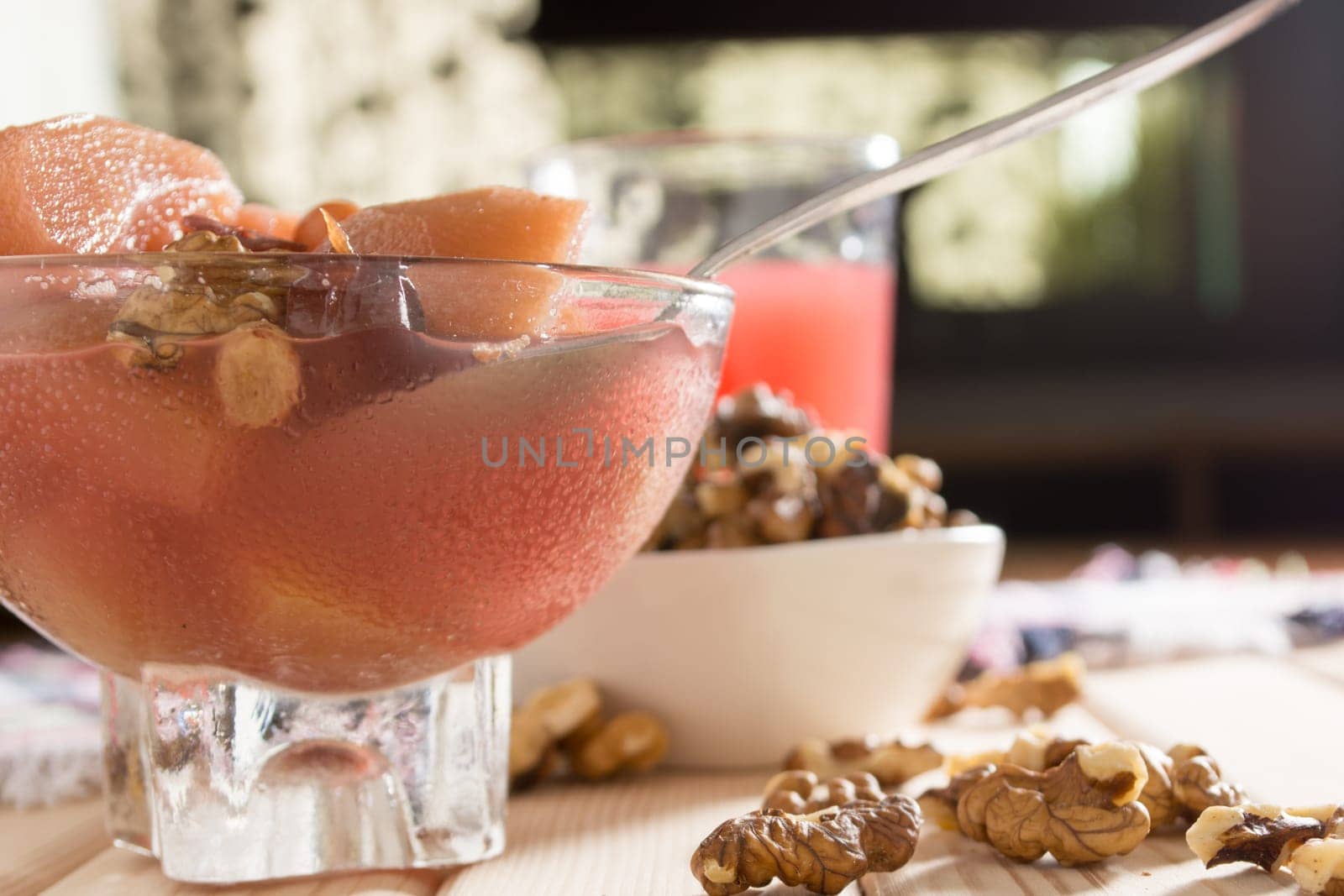 Apple compote with dried fruits in the cup on wooden table with decorative wallnuts
