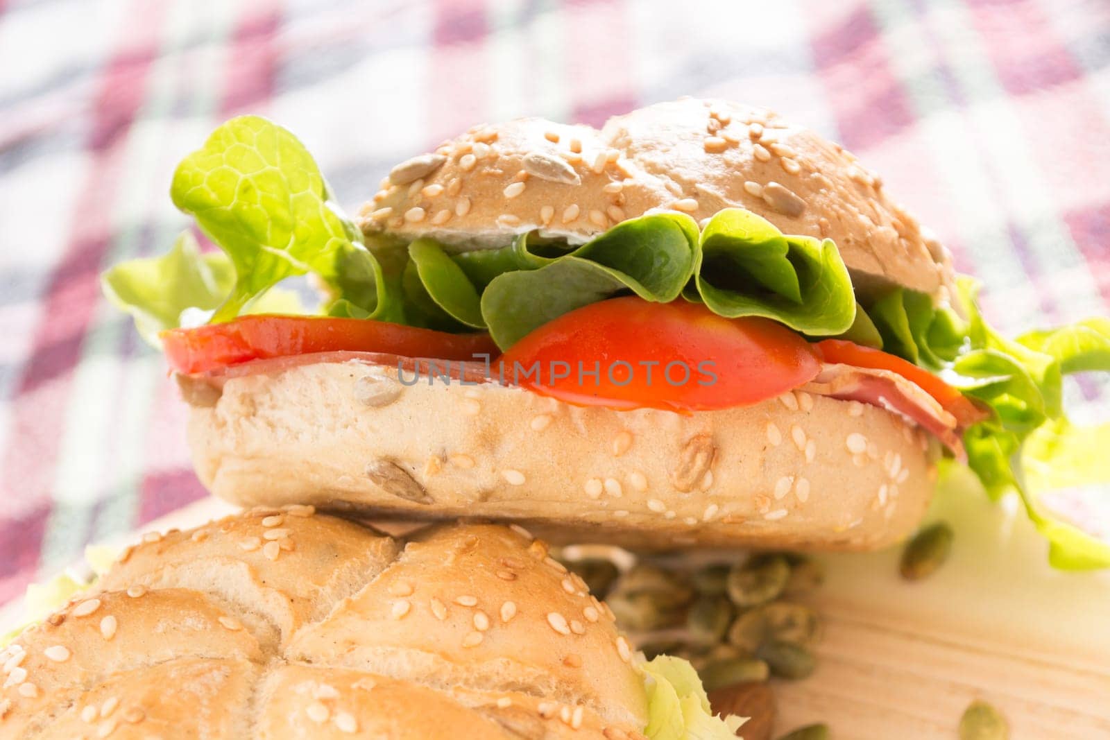 Sandwich with fresh smoked meat, cheese, lettuce and tomato with homemade ketchup arranged with almond and pumpkin seeds