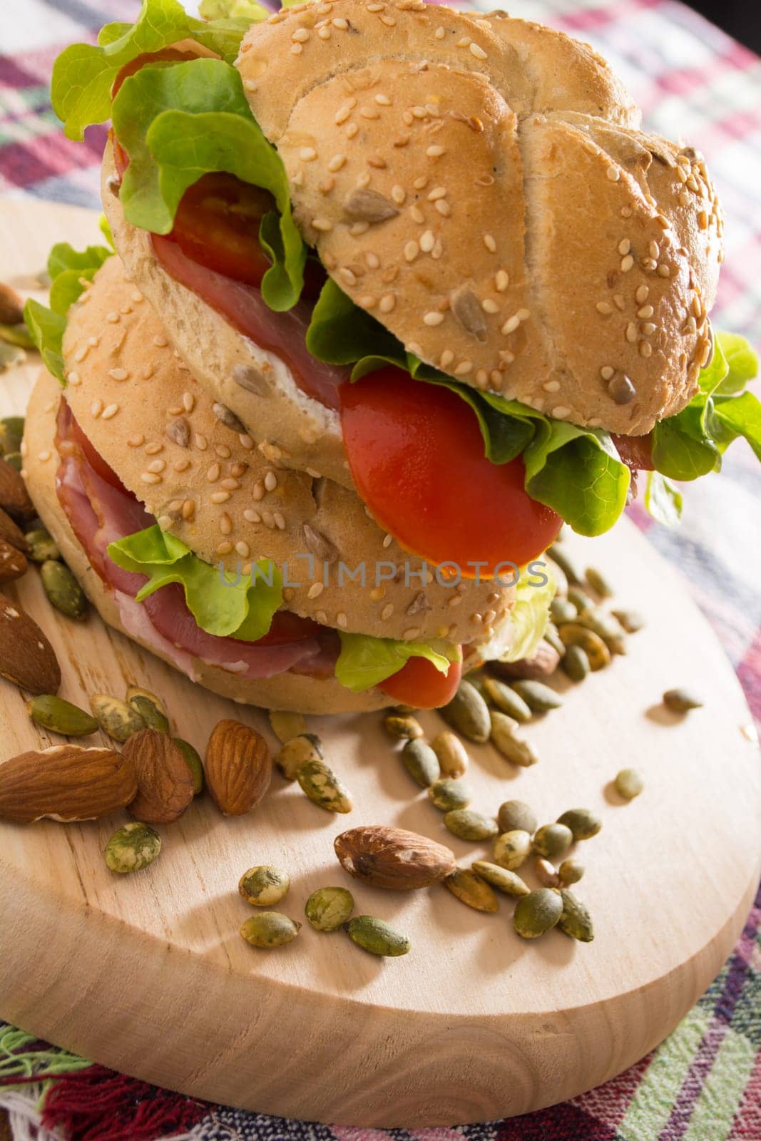 Stacked sandwiches with fresh smoked meat, cheese, lettuce and tomato with homemade ketchup arranged with almond and pumpkin seeds