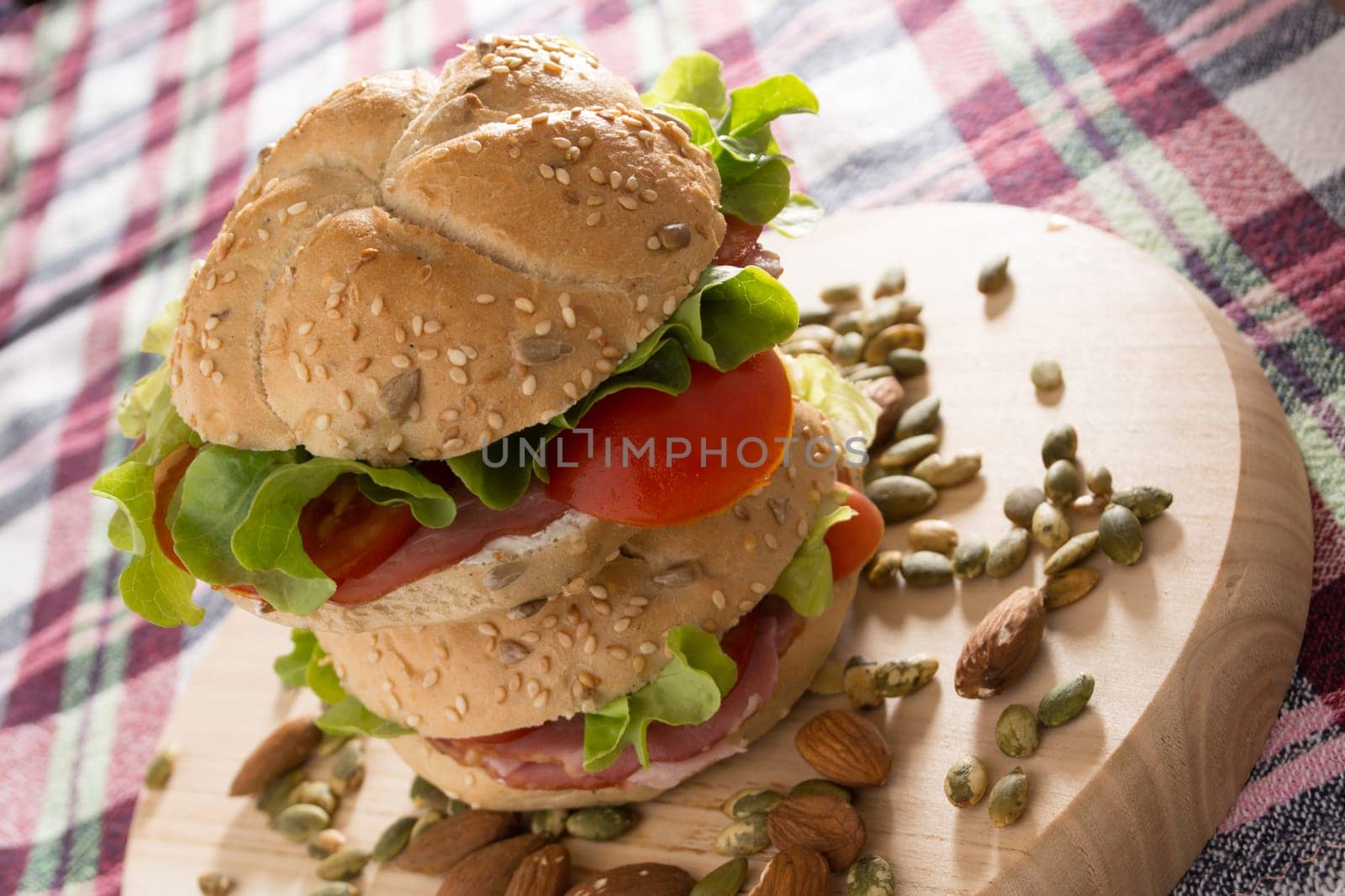 Stacked sandwiches with fresh smoked meat, cheese, lettuce and tomato with homemade ketchup arranged with almond and pumpkin seeds