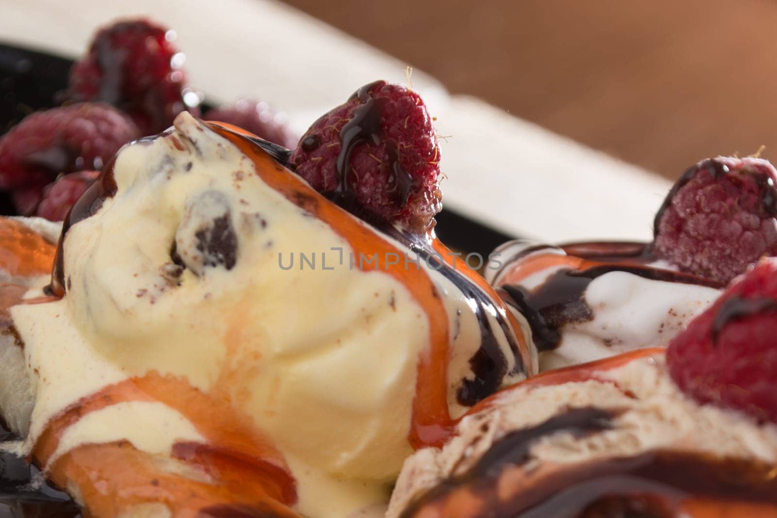 Fresh, golden pancakes with fruit and cream on a black plate with blurred background