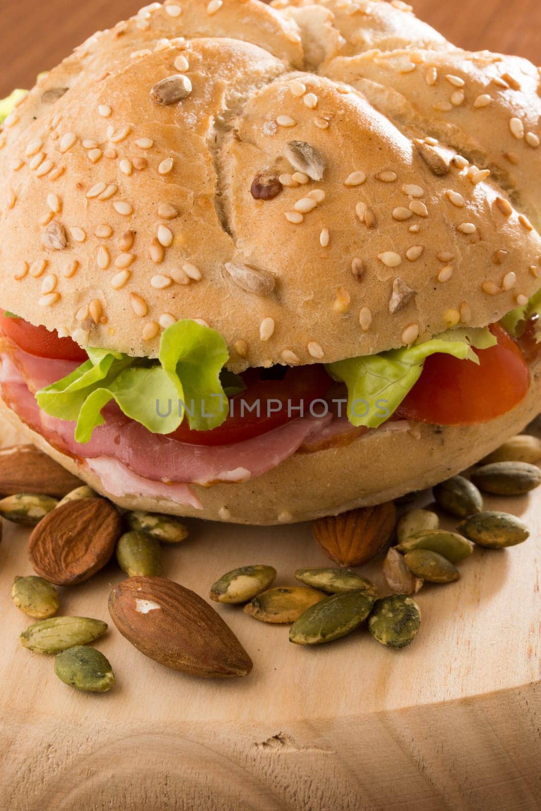 Sandwich with fresh smoked meat, cheese, lettuce and tomato with homemade ketchup arranged with almond and pumpkin seeds