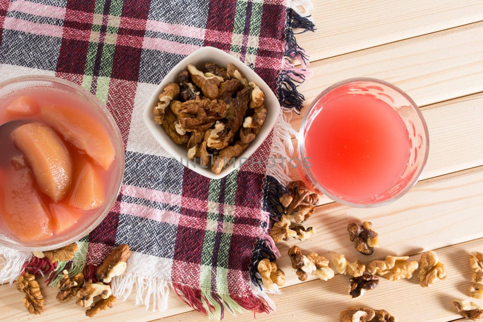 Apple compote with dried fruits in the cup on wooden table with decorative wallnuts