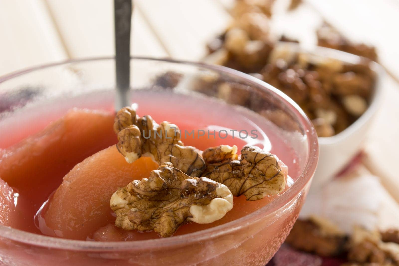 Apple compote with dried fruits in the cup on wooden table with decorative wallnuts