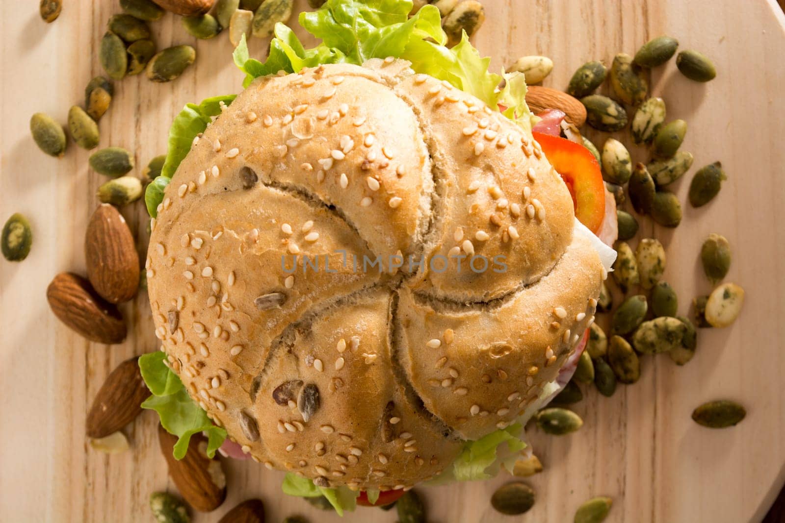 Sandwich with fresh smoked meat, cheese, lettuce and tomato with homemade ketchup arranged with almond and pumpkin seeds
