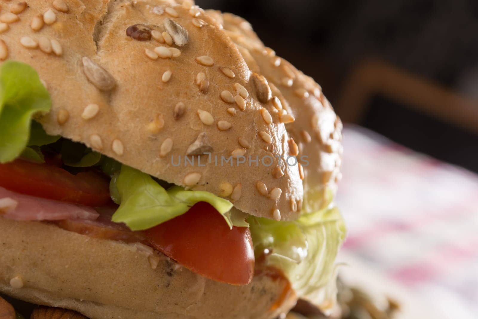 Sandwich with fresh smoked meat, cheese, lettuce and tomato with homemade ketchup arranged with almond and pumpkin seeds
