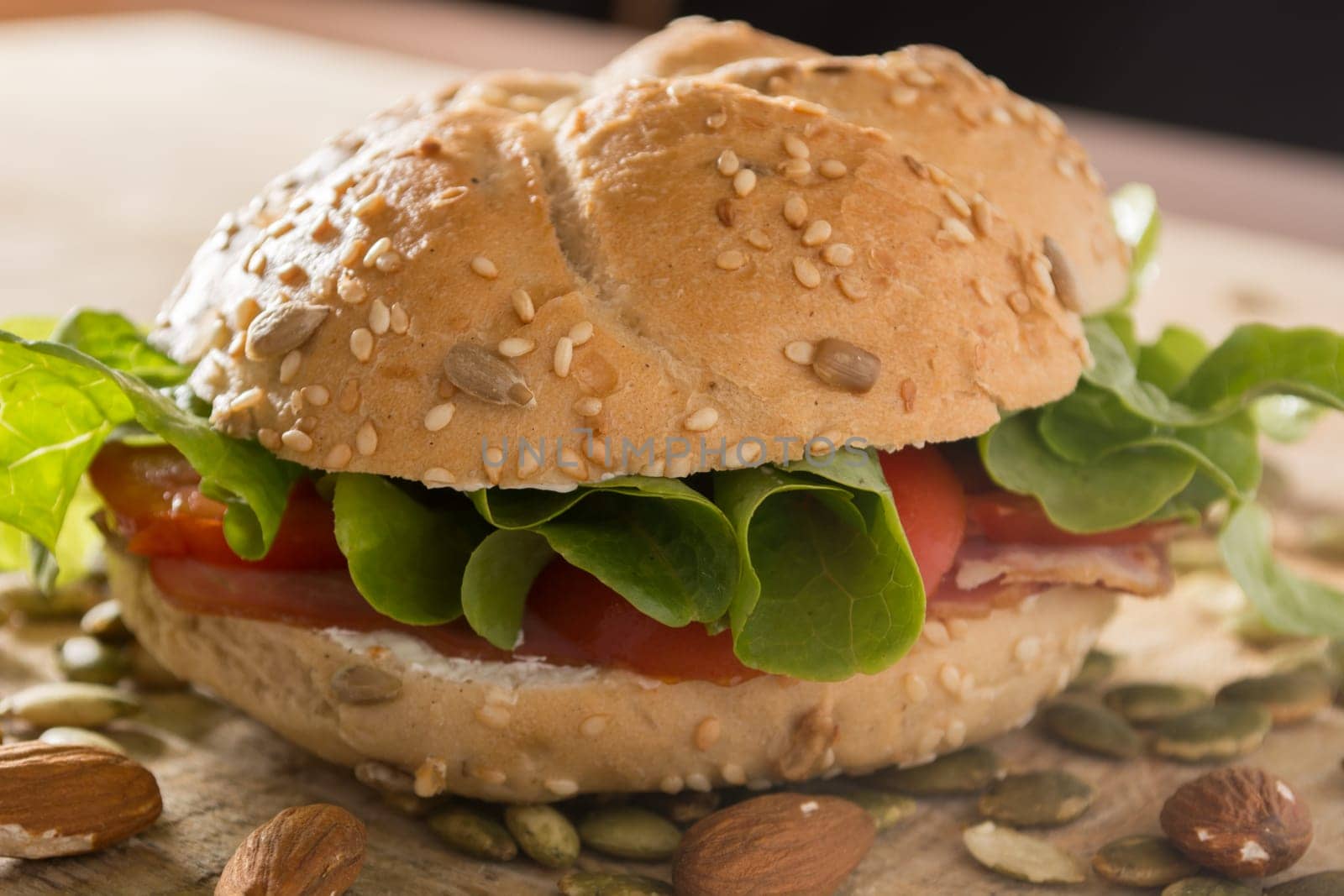 Sandwich with fresh smoked meat, cheese, lettuce and tomato with homemade ketchup arranged with almond and pumpkin seeds