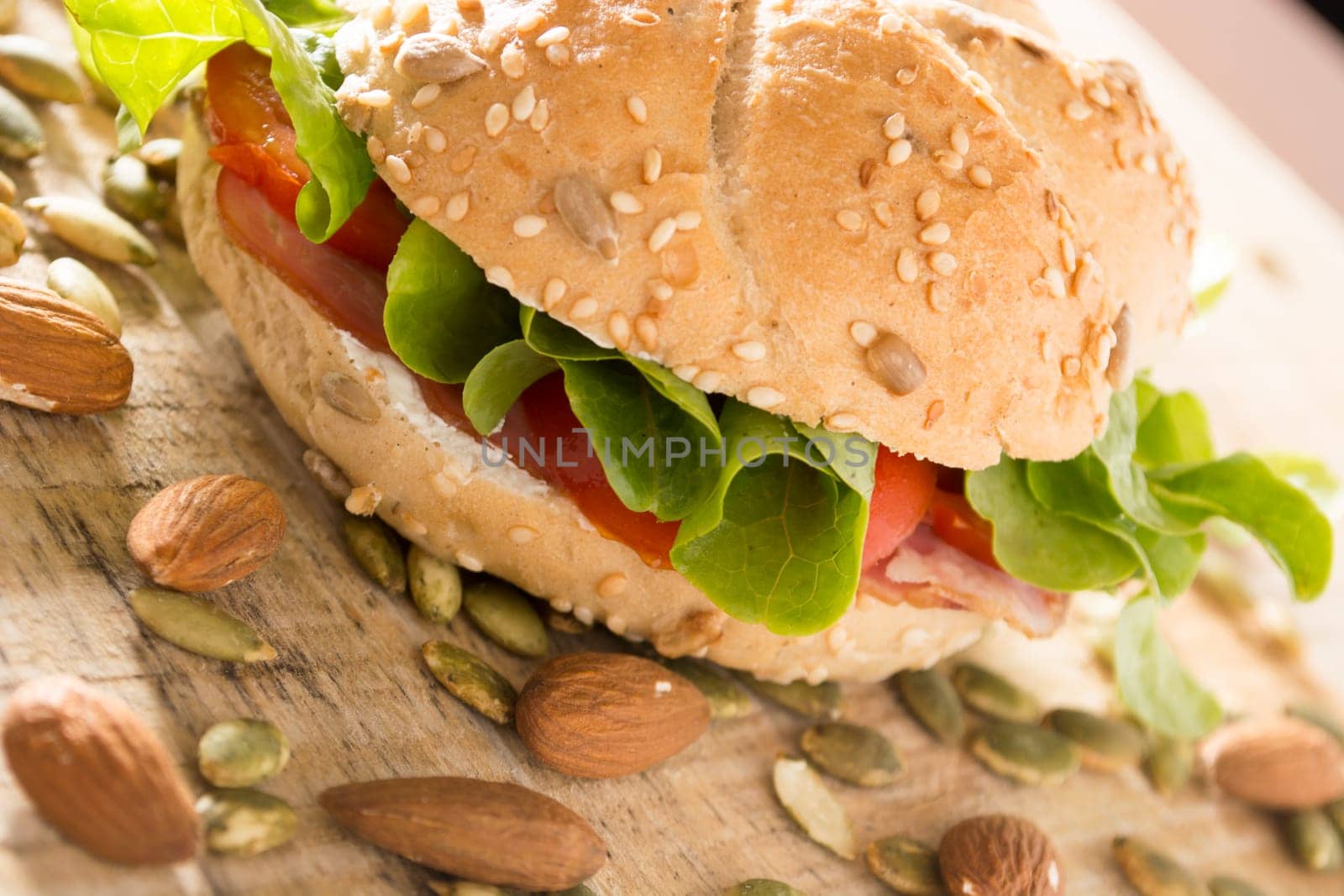 Sandwich with fresh smoked meat, cheese, lettuce and tomato with homemade ketchup arranged with almond and pumpkin seeds