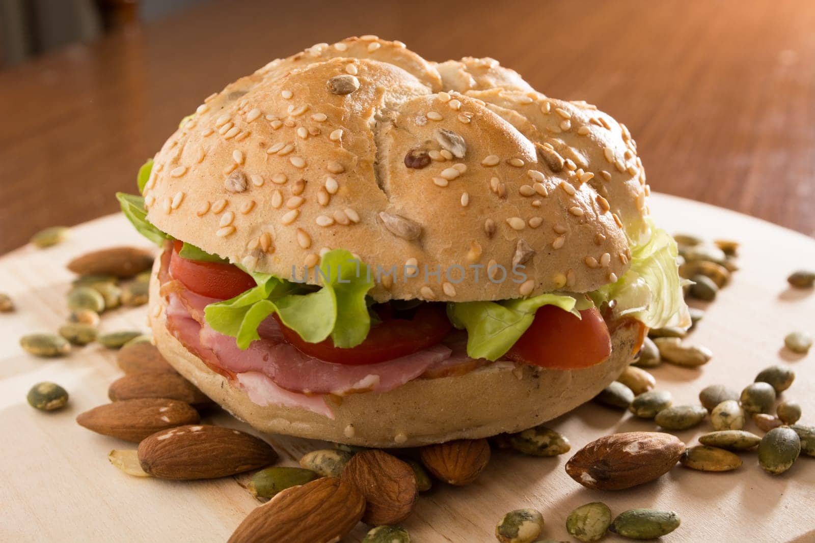 Sandwich with fresh smoked meat, cheese, lettuce and tomato with homemade ketchup arranged with almond and pumpkin seeds