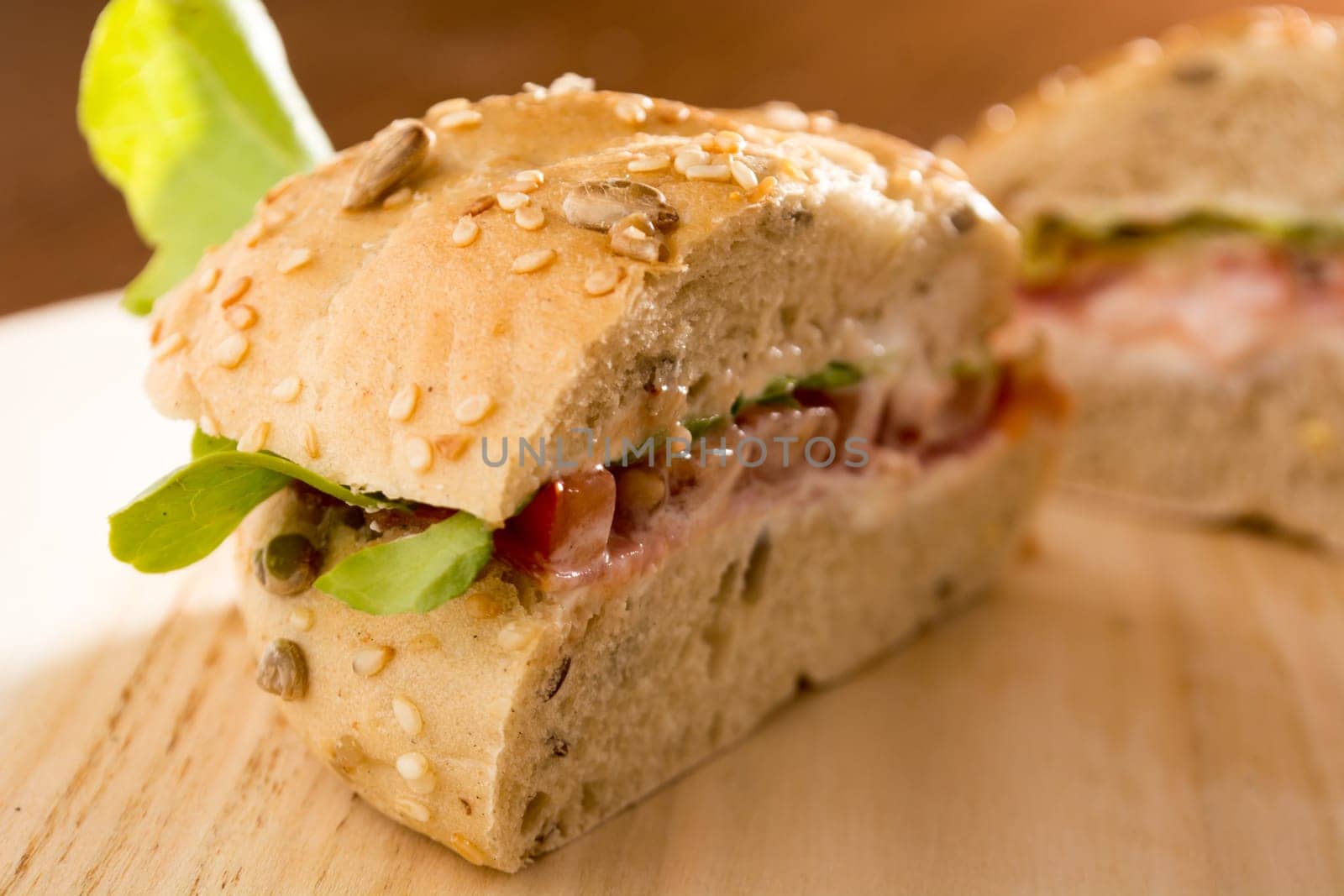 Sandwich with fresh smoked meat, cheese, lettuce and tomato with homemade ketchup sliced in half