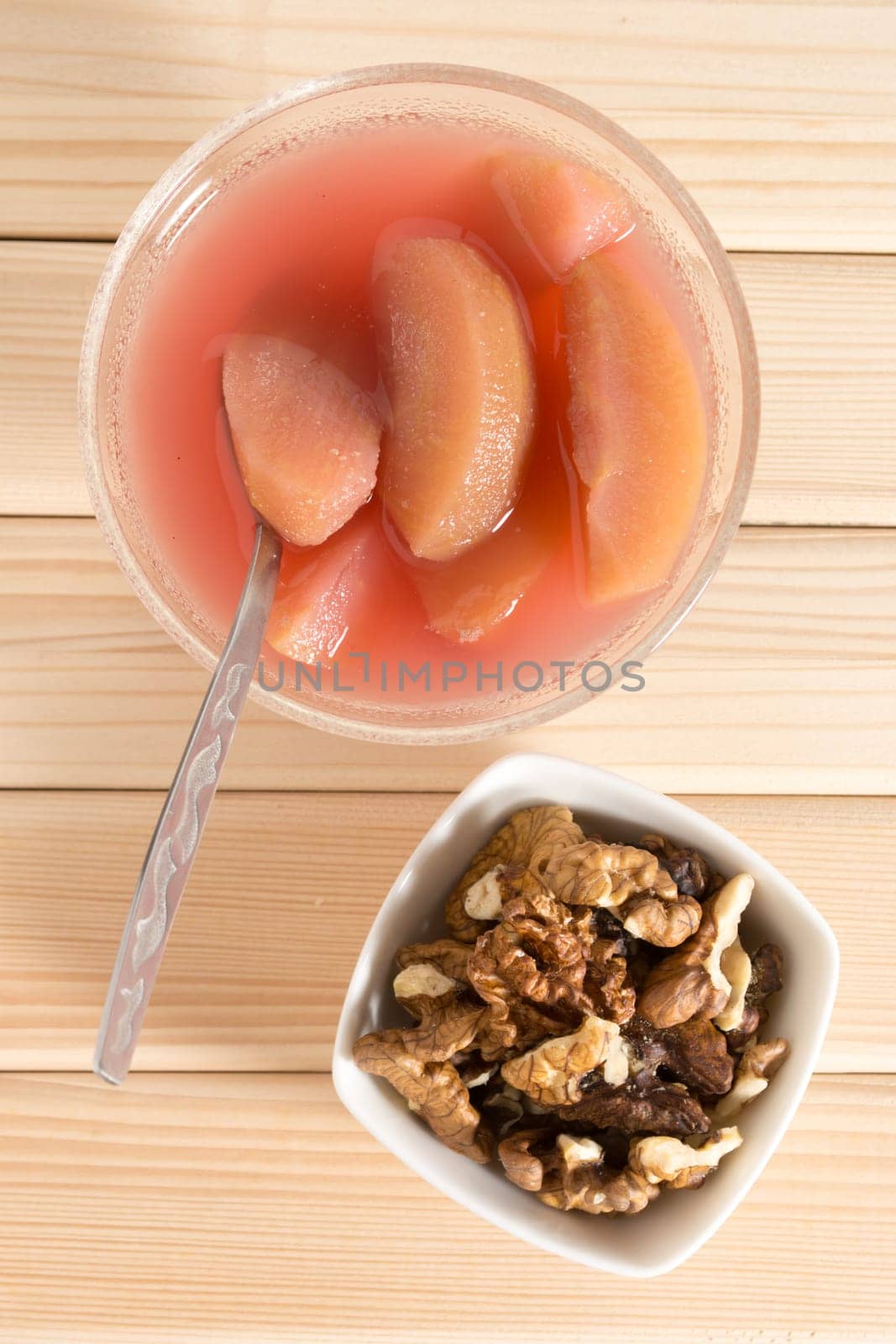 Apple compote with dried fruits in the cup on wooden table with decorative wallnuts