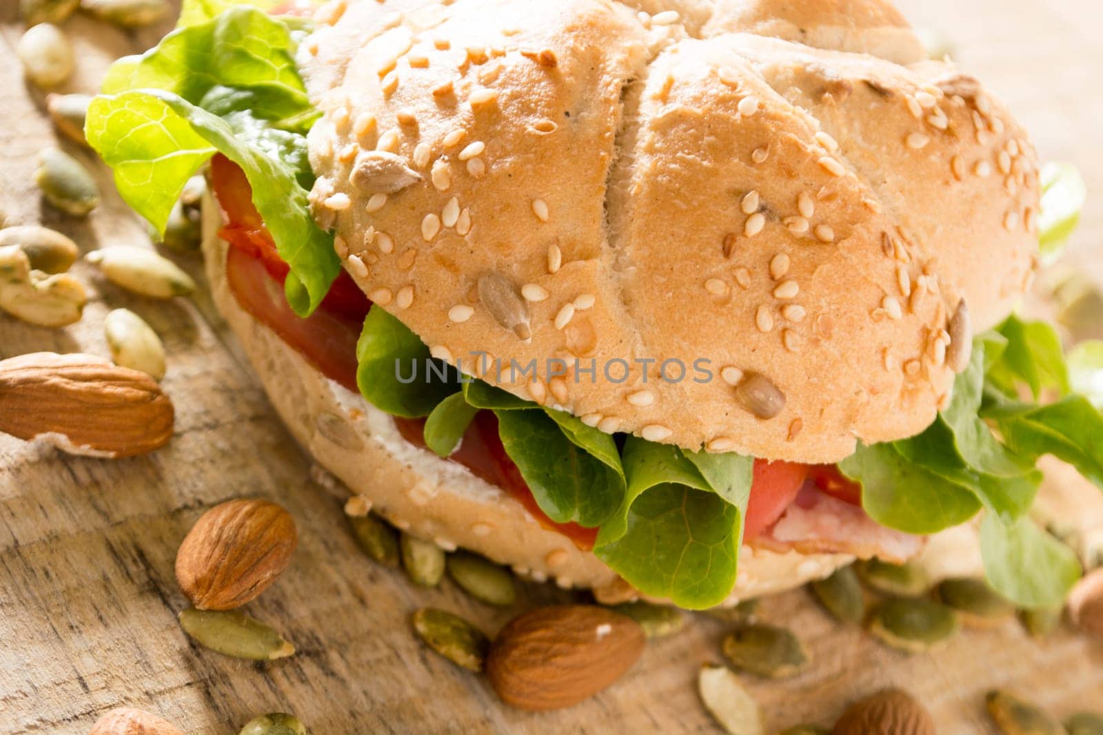 Sandwich with fresh smoked meat, cheese, lettuce and tomato with homemade ketchup arranged with almond and pumpkin seeds