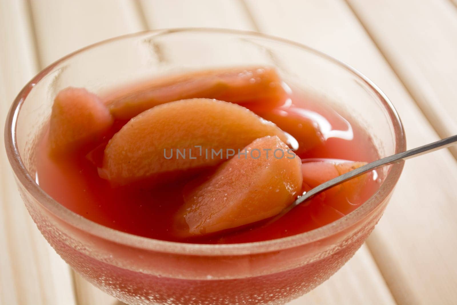 Apple compote on wooden table with spoon in the cup