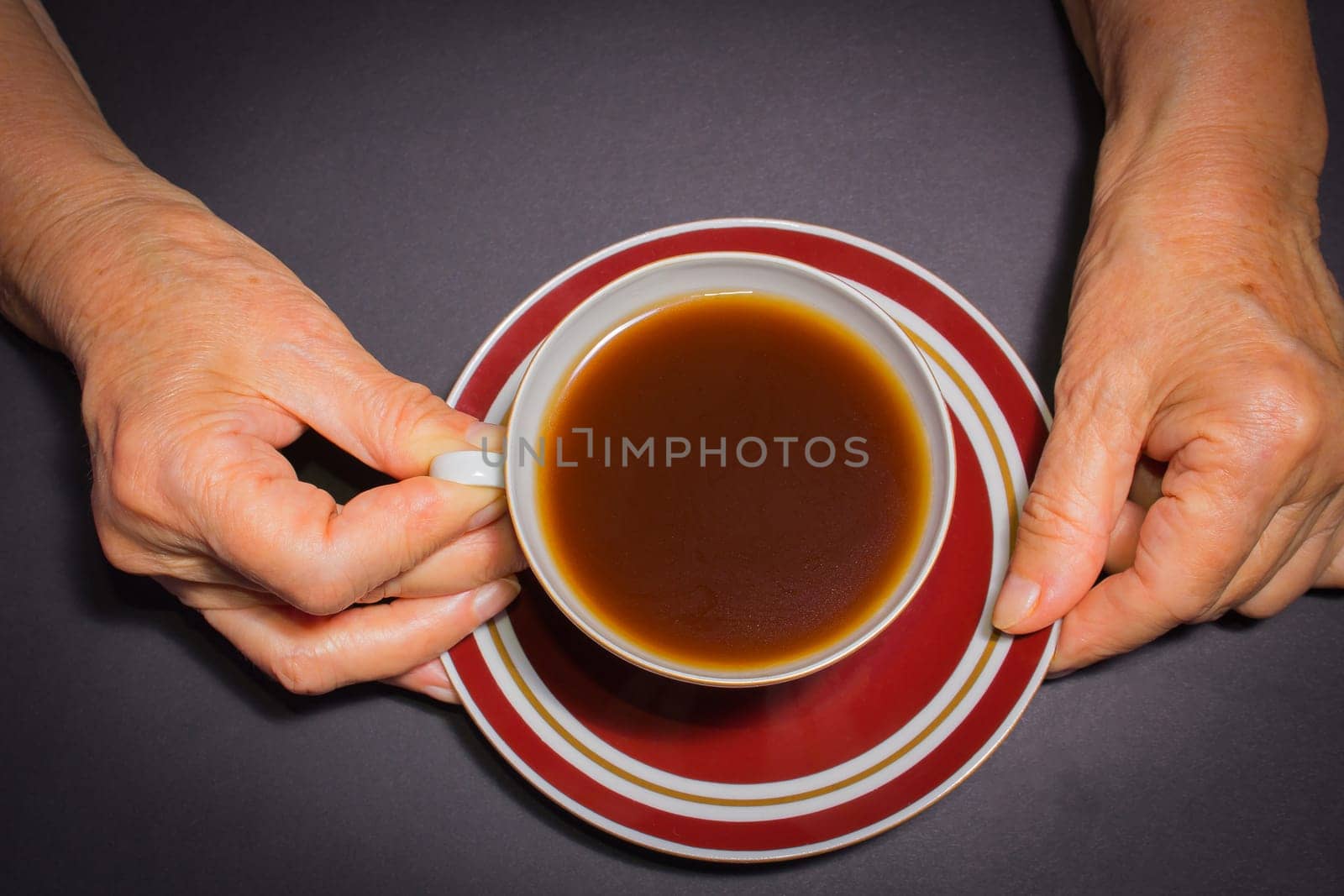 The female hands of an old woman with a cup of coffee