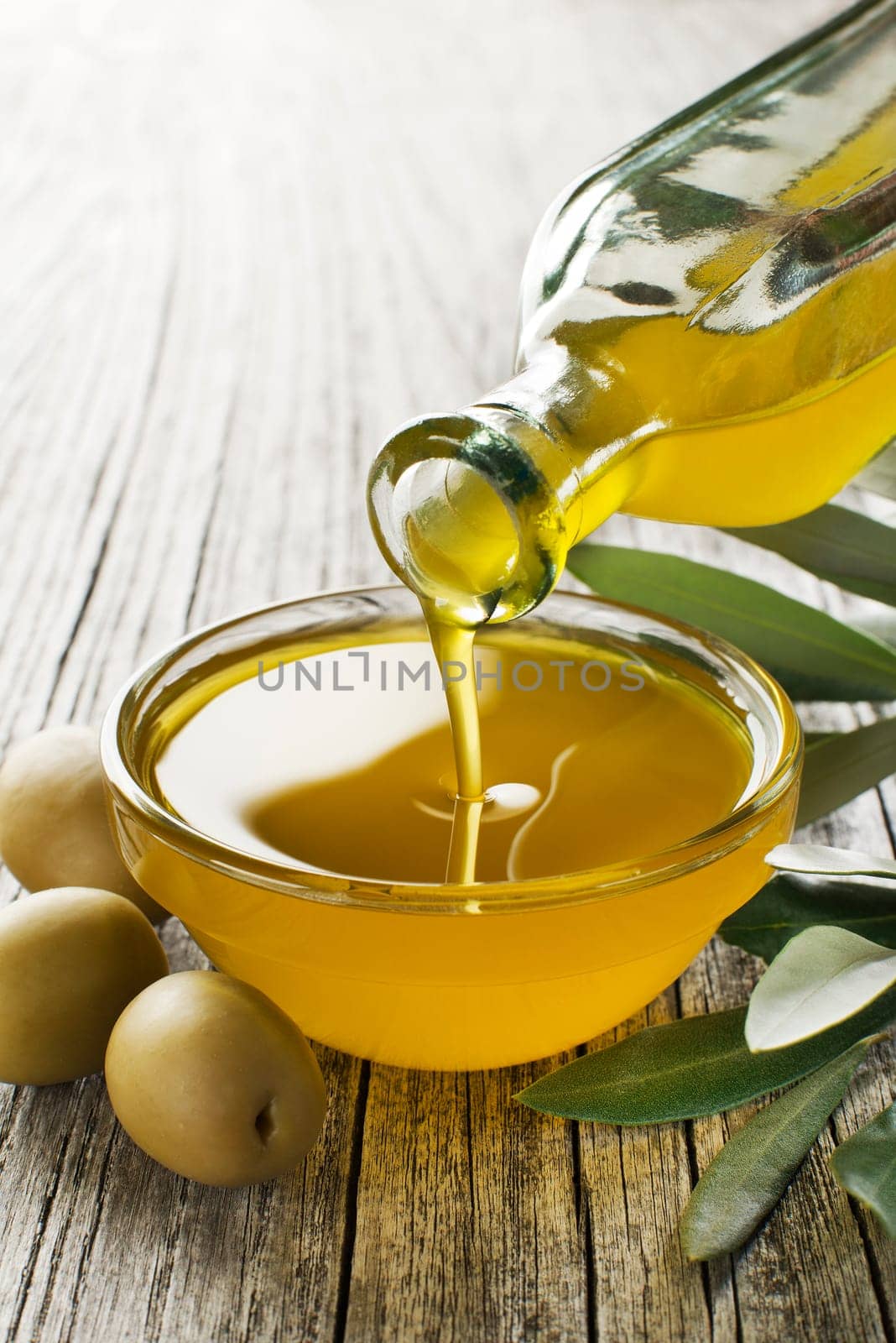 Bottle pouring virgin olive oil in a bowl close up