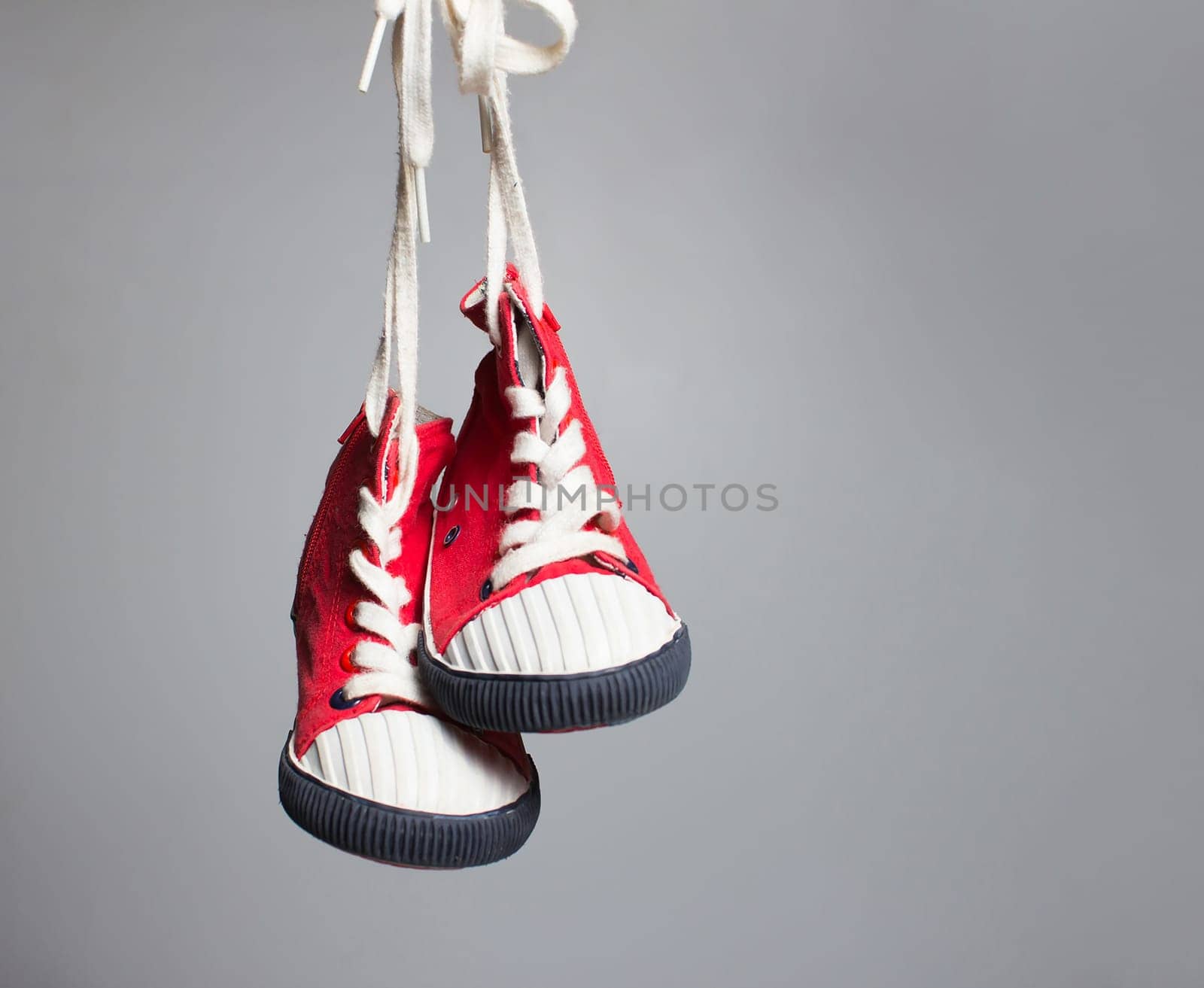 Sport baby shoes hanging on the gray background