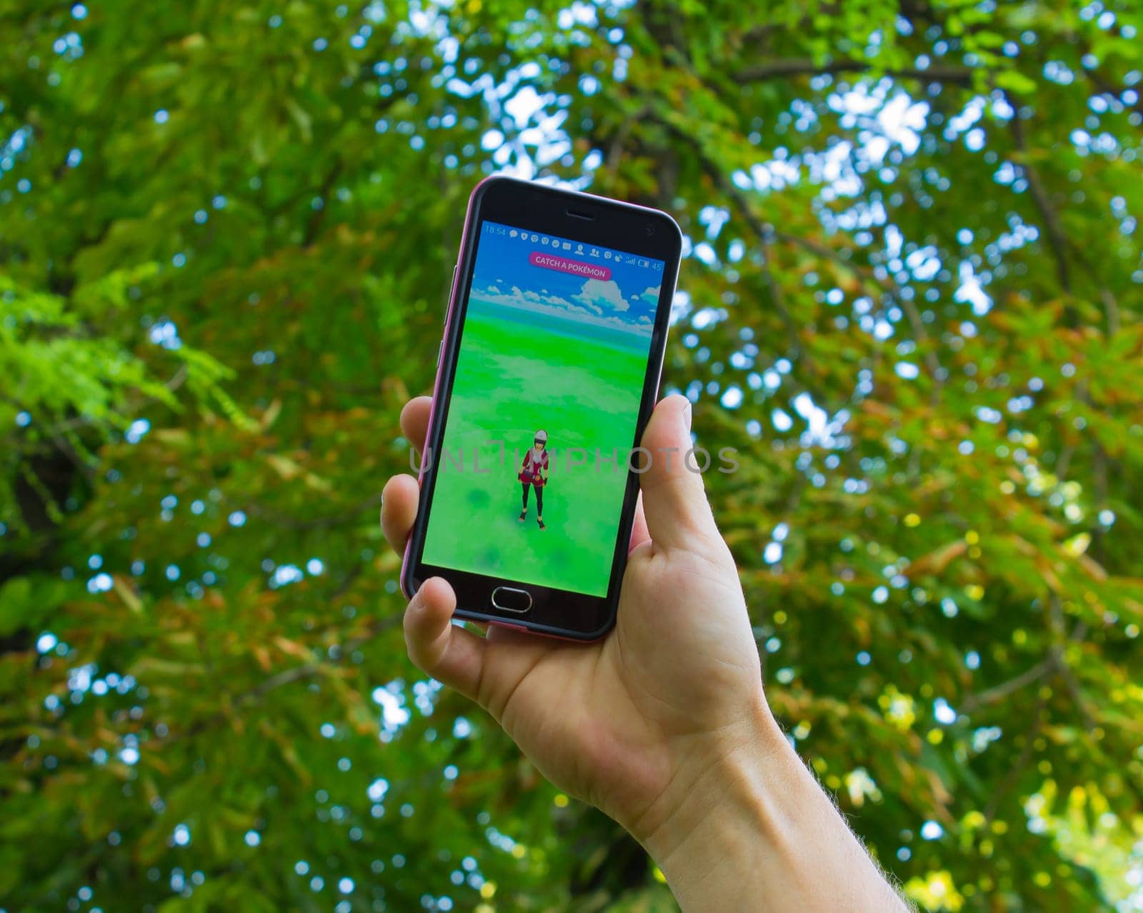 Dnipropetrovsk, Ukraine - July 23, 2016: The male hand holding phone with game Pokemon GO - a free-to-play augmented reality mobile game developed by Niantic for iOS and Android devices.